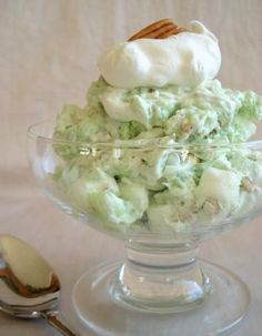 a glass bowl filled with ice cream next to a spoon on a white tablecloth