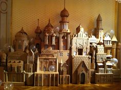 a collection of wooden model buildings sitting on top of a hard wood floor next to a wall