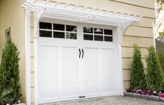 a white garage door with two windows in front of a house