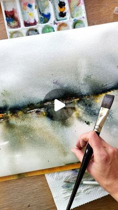 a person is painting with watercolors on a canvas and holding a paintbrush