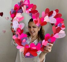 a woman holding up paper hearts in front of her face and smiling at the camera