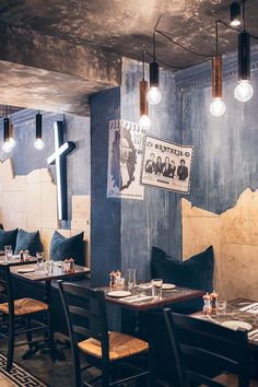 an empty restaurant with blue walls and wooden tables set up for two people to eat