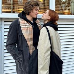 two people standing next to each other in front of a window and one person wearing a scarf