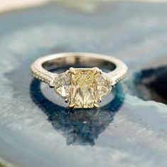 an engagement ring with three stone accents on a marble slab, close - up view