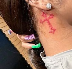 a woman with ear piercings has a cross tattoo on her left side behind her ear