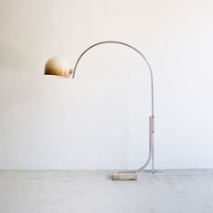 a lamp that is on top of a cement floor in front of a white wall