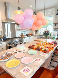 a kitchen island with plates and balloons hanging from the ceiling