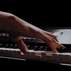 a person's hand on top of a piano with the keys pointed up to it