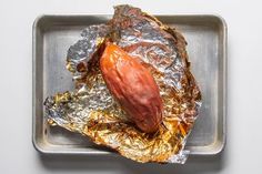 a hot dog wrapped in foil sitting on top of a metal pan