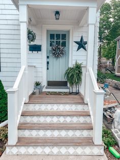 a white house with steps leading up to the front door and star decorations on the porch