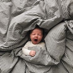 a baby is laying in bed with its mouth open and eyes wide open as it sleeps