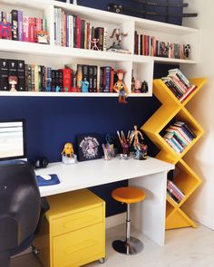 a white desk topped with a computer monitor next to a yellow shelf filled with books