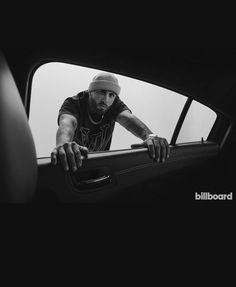 a man leaning out the window of a car with his hand on the door handle