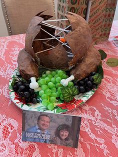 a table topped with a plate covered in fruit and vegetables next to a photo frame