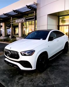 a white mercedes suv parked in front of a building