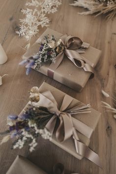 two wrapped presents sitting on top of a wooden table next to dried flowers and candles