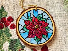 a stained glass ornament with a red flower on it