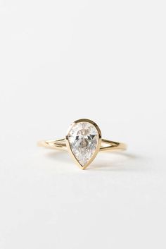 a pear shaped diamond ring in yellow gold with a single stone on the side and a thin band