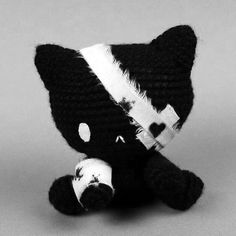 a black and white crocheted stuffed animal sitting on top of a gray surface