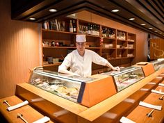 a man standing behind a counter filled with food