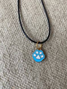 "This super cute, small enameled blue paw print pendant is great for that cat or dog lover in your life. It is strung along a 20-22\" length black cord. This can be placed on 18-20\" black cord if requested for no additional charge. This is an absolutely gorgeous pendant and would be a great birthday present, anniversary present, Mother's Day gift, Christmas present, or graduation gift. The sleek design of this pendant will turn heads and make you take a second look! (Hand strung item) Like what you see? View more at: https://www.etsy.com/shop/StephsCraftingBits" Blue Cat Design Jewelry For Gift, Blue Cat Design Jewelry As Gift, Blue Jewelry With Cat Design For Gift, Paw Print Pendant, Paw Necklace, Paw Print Necklace, Animals Dog, Enamel Necklaces, Anniversary Present