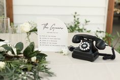 an old fashioned phone sitting on top of a table next to a vase with flowers