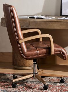 a brown leather office chair sitting on top of a wooden desk