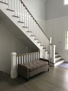 a couch sitting under a stair case in a living room next to a door and window