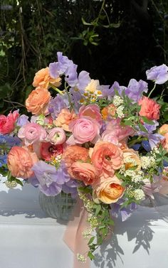 a vase filled with lots of different colored flowers on top of a white cloth covered table