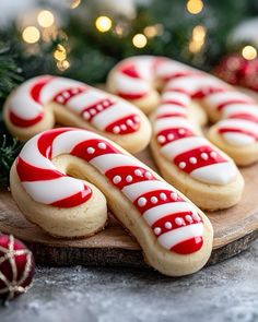 cookies decorated with white and red icing on a wooden board next to christmas decorations