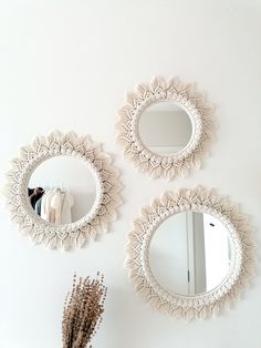 three round mirrors hanging on the wall next to a vase with dried flowers in it