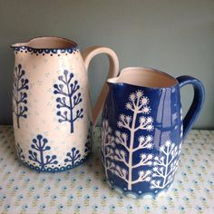 two blue and white pitchers sitting on top of a table next to eachother