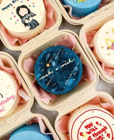 many decorated cupcakes in small trays with writing on the top and bottom