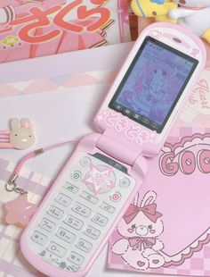 a pink cell phone sitting on top of a table next to a keychain