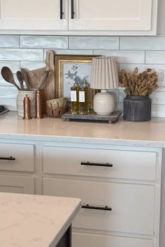 a kitchen counter with white cabinets and gold accessories on it, including an old clock