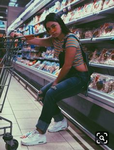 a woman sitting on top of a shopping cart in a grocery store