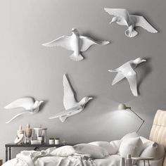 white birds flying in the air above a bed