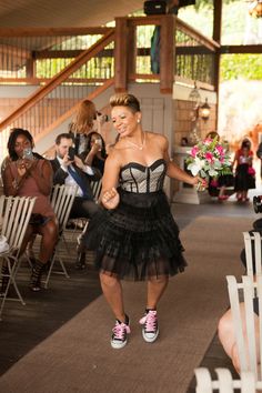 a woman in a black dress walking down the aisle