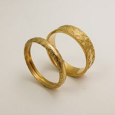 two gold wedding rings sitting next to each other