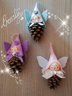 three small pine cones are decorated with little fairy dolls and one is holding a cone