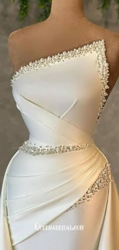 a white wedding dress with beading on the waist and shoulder, draped over it