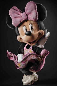 a minnie mouse figurine holding a cell phone in her right hand and wearing a pink dress