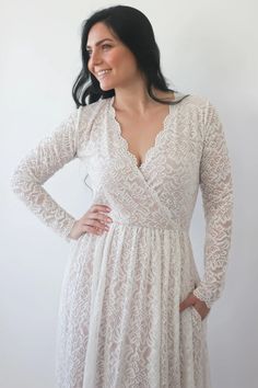 a woman in a white dress is standing with her hands on her hips and smiling