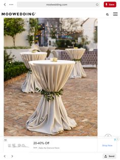 an image of a table set up with white linens and greenery on it