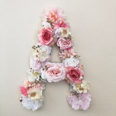 the letter is made out of flowers and has pink, white, and peach colors