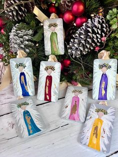 christmas ornaments with angels and pine cones in the background on a white wooden table next to evergreens