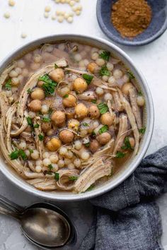 a bowl filled with beans and meat next to two spoons