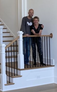 a man and woman standing on top of a stair case next to a banister