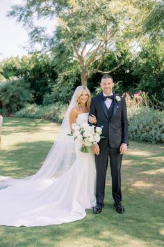 a bride and groom standing in the grass at their wedding ceremony, posing for a photo