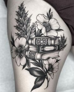 a woman's thigh with books and flowers on her thighs, in black and white